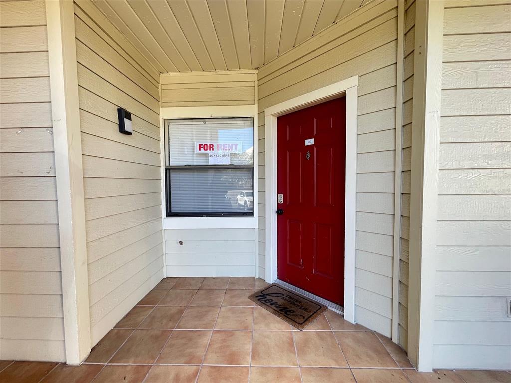 A red front door and a window with a for rent sign on a porch — 3008 PARKWAY BOULEVARD UNIT 107, KISSIMMEE, FL