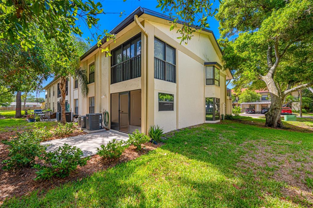 The exterior of a two-story apartment building features a screened-in patio and green lawn — 11511 113TH STREET UNIT 10A, LARGO, FL