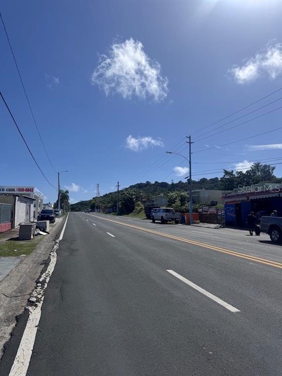 A paved road stretches into the distance under a blue sky with scattered clouds — Vistas Del Convento CALLE 3, FAJARDO, PR
