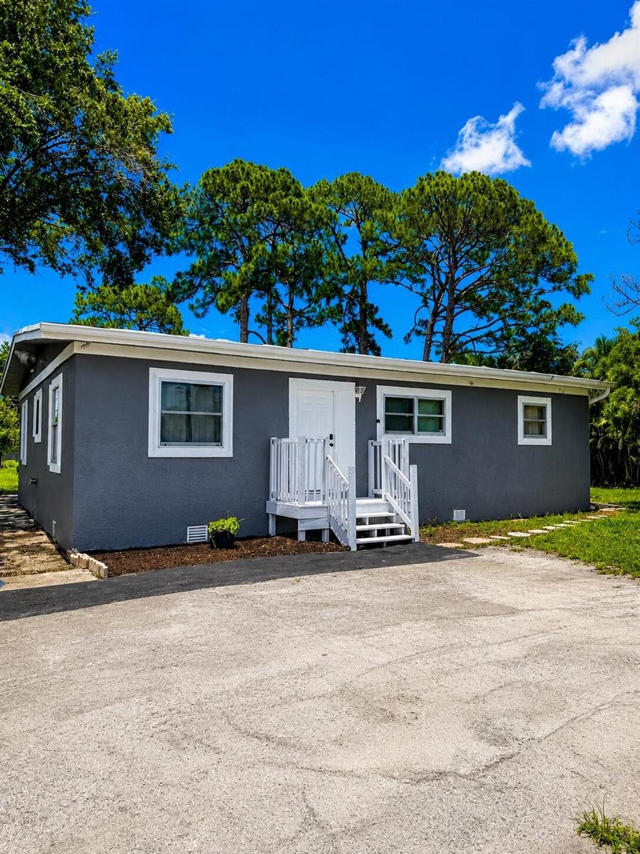 A gray single-story house features a white front door, stairs, and a paved driveway — 468 N 53rd Dr Drive N, FL 33415, FL