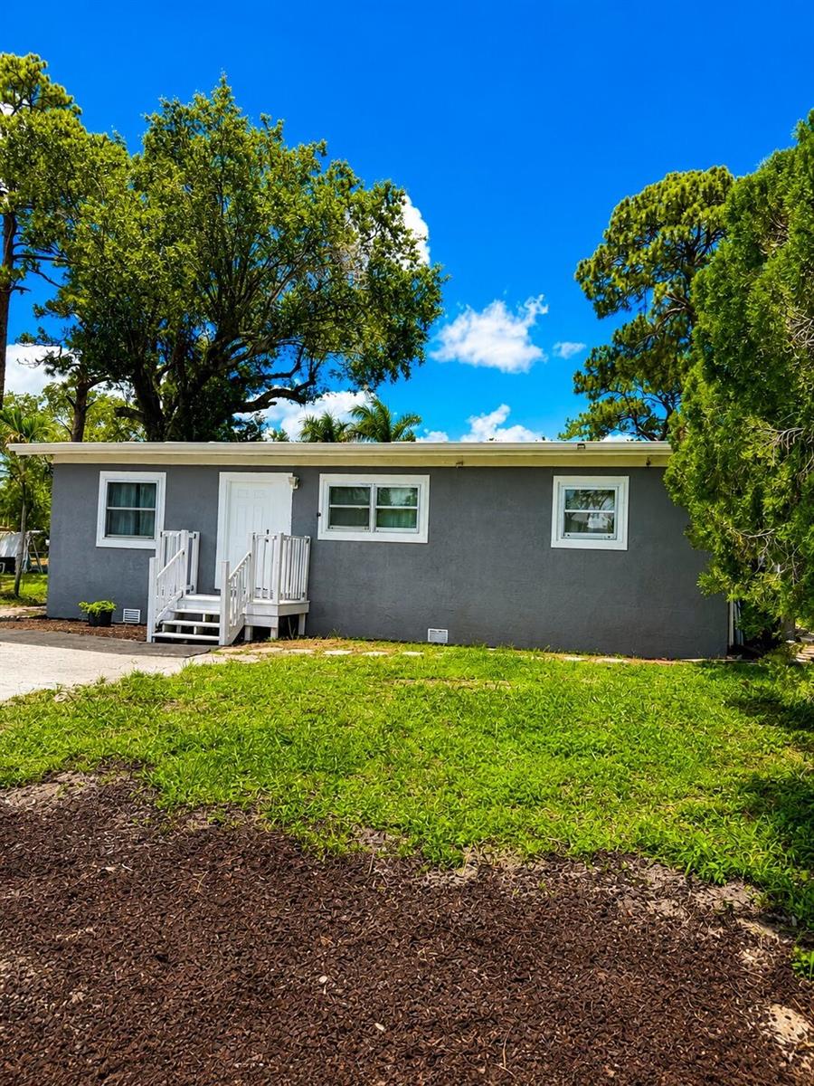 A gray, single-story house with a white door, white stairs, and three white-trimmed windows — 468 N 53rd Dr Drive N, FL 33415, FL