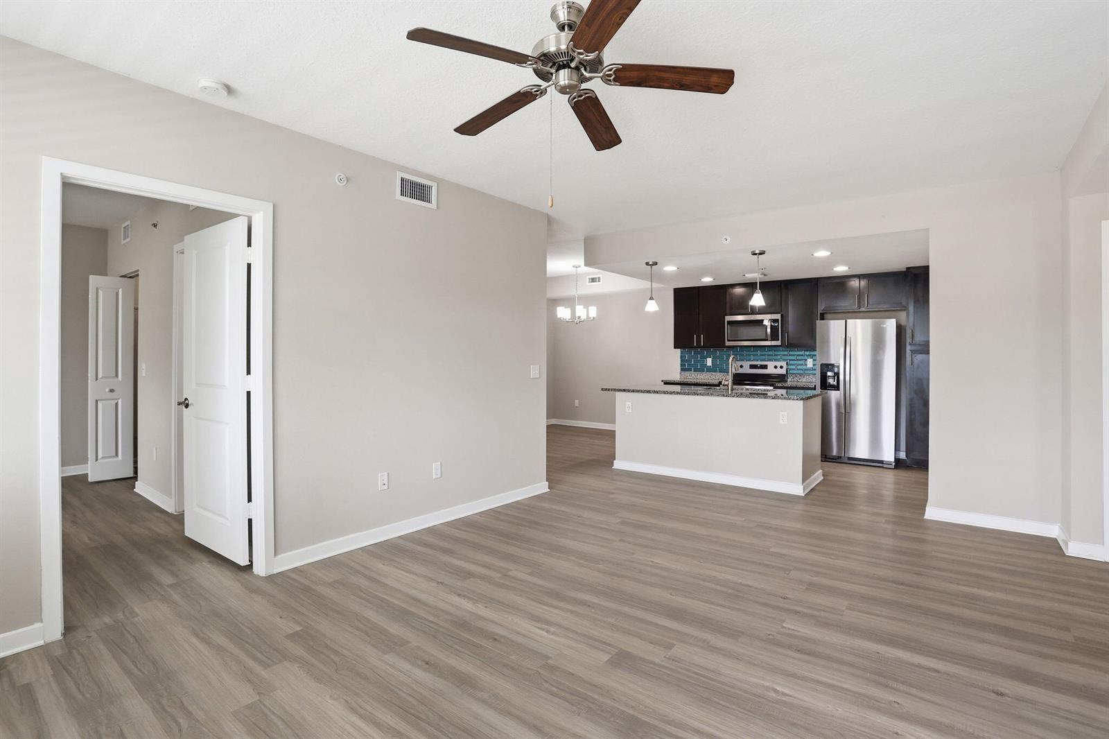 An open-concept living area features wood-look flooring, a ceiling fan, and a kitchen with island — 3611 High Ridge Way # 302, Boynton Beach FL 33426, BOYNTON BEACH, FL