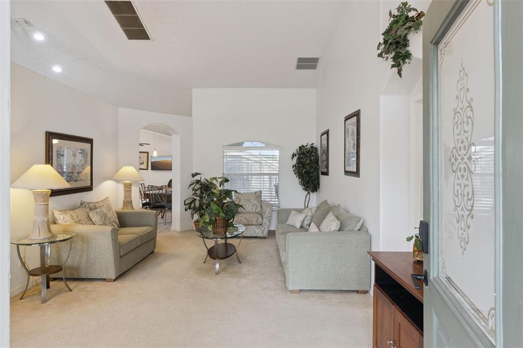 A living room with light-colored carpet, two sofas, a coffee table, and an arched entryway — 3144 IBIS HILL STREET, CLERMONT, FL