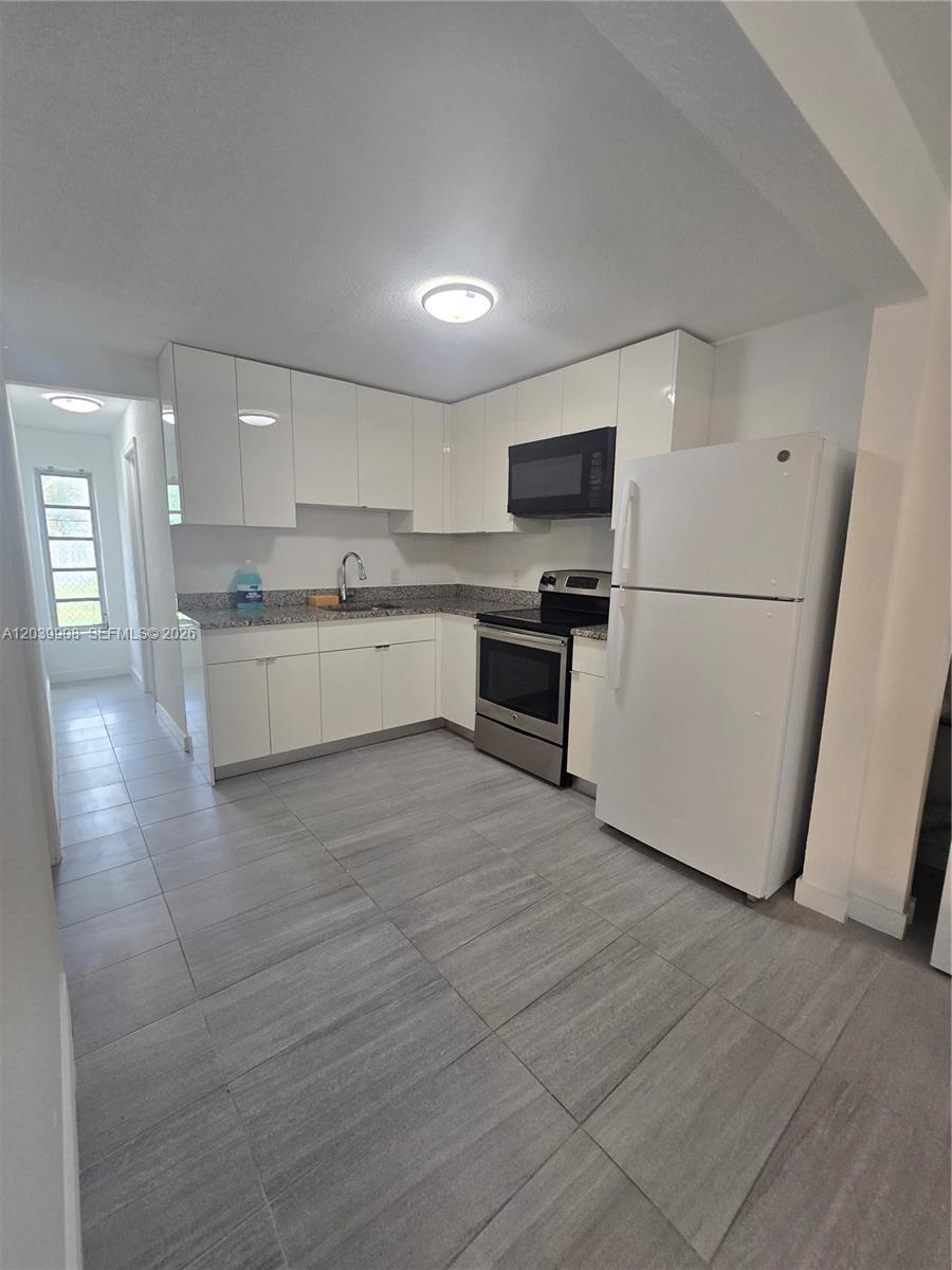 A kitchen features white cabinets, stainless steel appliances, granite countertops, and light gray tile flooring — 237 SW 13th St # 5, Dania Beach FL 33004, DANIA BEACH, FL