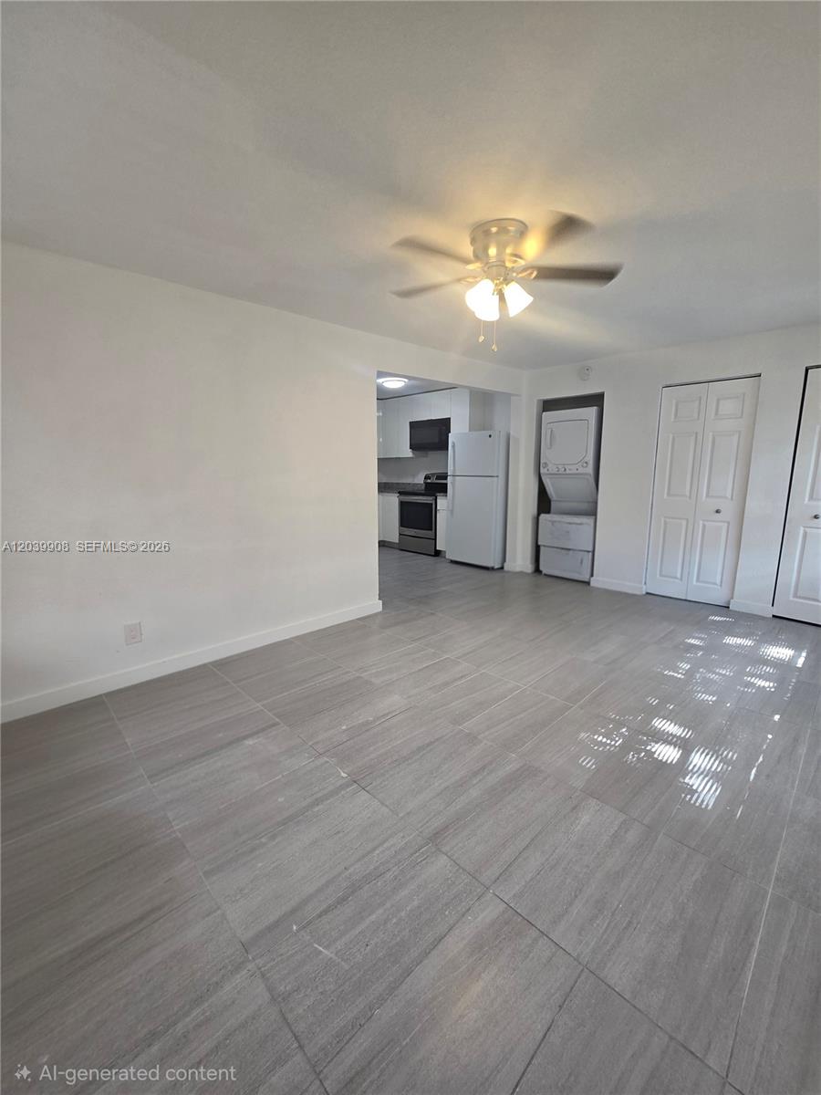 A tiled living area opens into a kitchen with white cabinets and a stacked washer-dryer — 237 SW 13th St # 5, Dania Beach FL 33004, DANIA BEACH, FL
