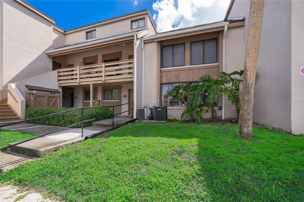A two-story apartment building exterior features a wooden balcony, a ramp, and landscaping — 228 ORIENTA POINT STREET UNIT 228, ALTAMONTE SPRINGS, FL