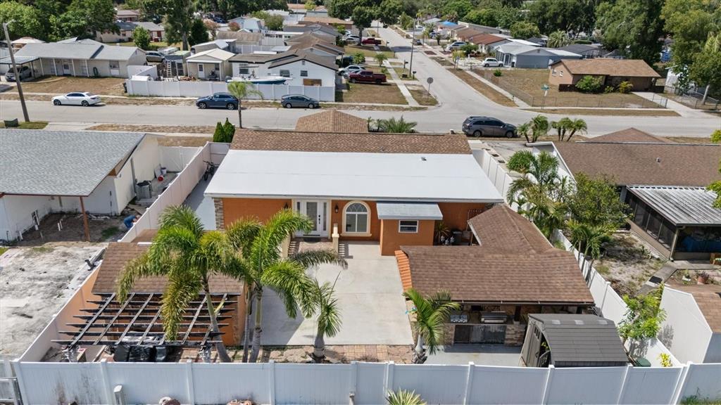 An aerial view shows an orange house with a white roof, patio, and palm trees — 8318 DRYCREEK DRIVE, TAMPA, FL