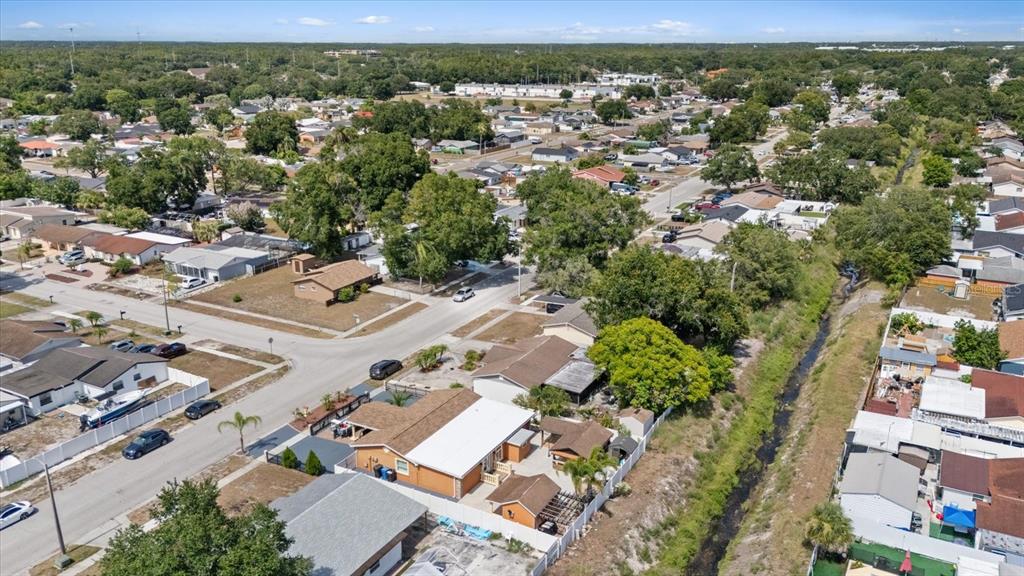 An aerial view shows a residential neighborhood with houses, streets, and a drainage canal — 8318 DRYCREEK DRIVE, TAMPA, FL