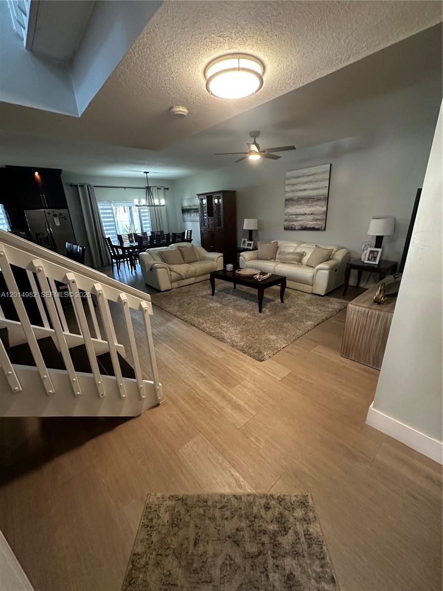 A living room features light wood flooring, a white sofa set, and a staircase — 8211 NW 191st Ln # 35L, Hialeah FL 33015, HIALEAH, FL