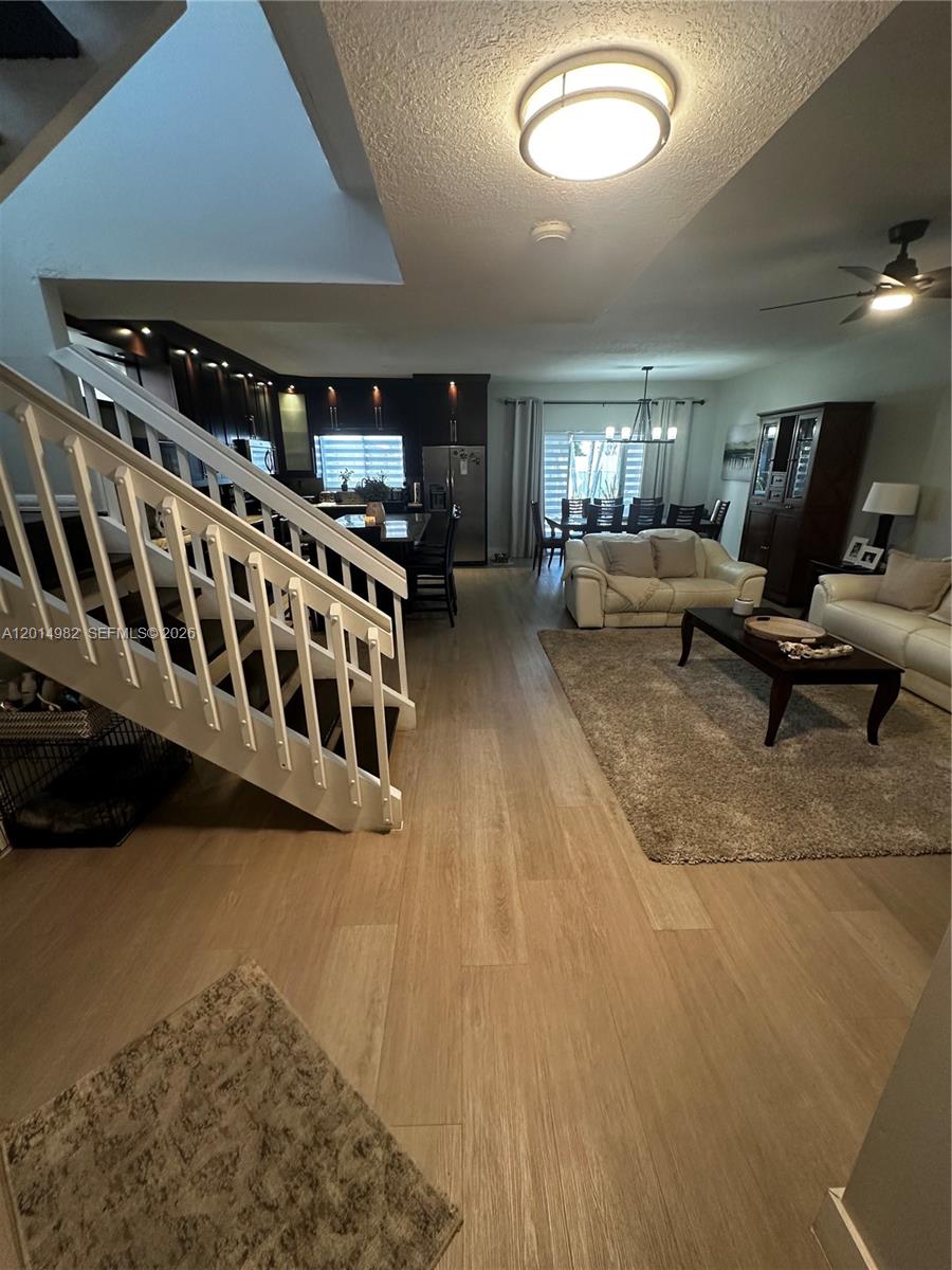 An open-concept living and dining area features wood-look flooring, a staircase, and dark kitchen cabinetry — 8211 NW 191st Ln # 35L, Hialeah FL 33015, HIALEAH, FL