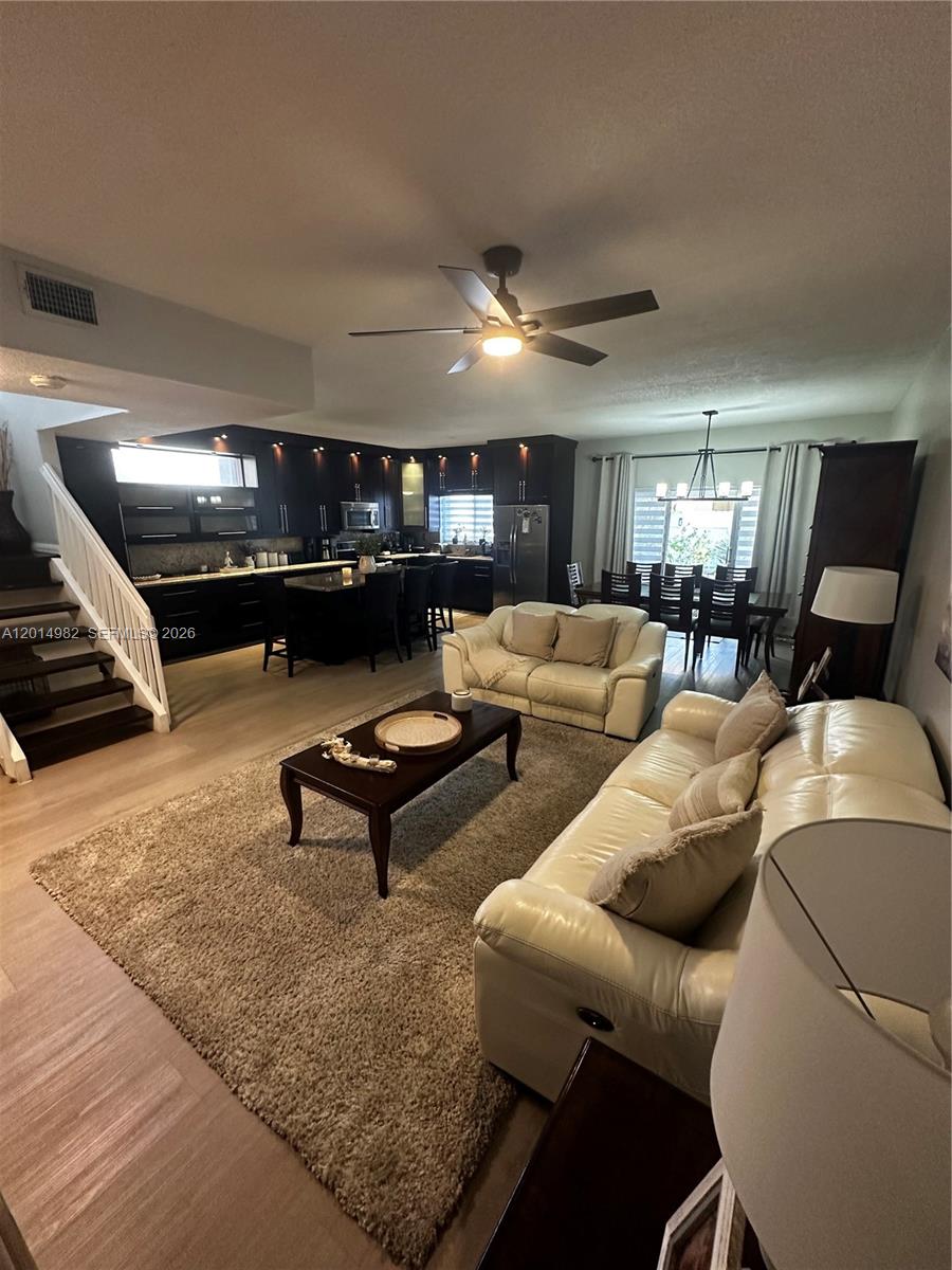 An open-concept living and dining area features dark cabinetry, light wood floors, and leather furniture — 8211 NW 191st Ln # 35L, Hialeah FL 33015, HIALEAH, FL
