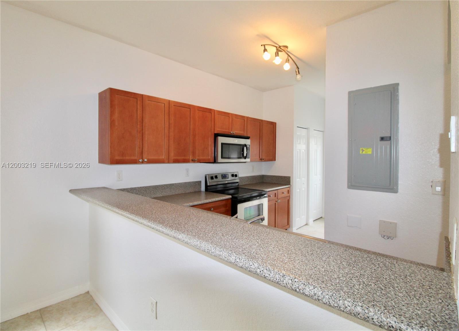 A kitchen features wooden cabinets, granite countertops, a microwave, and a stove — 14054 SW 49th St # 20, Miramar FL 33027, MIRAMAR, FL
