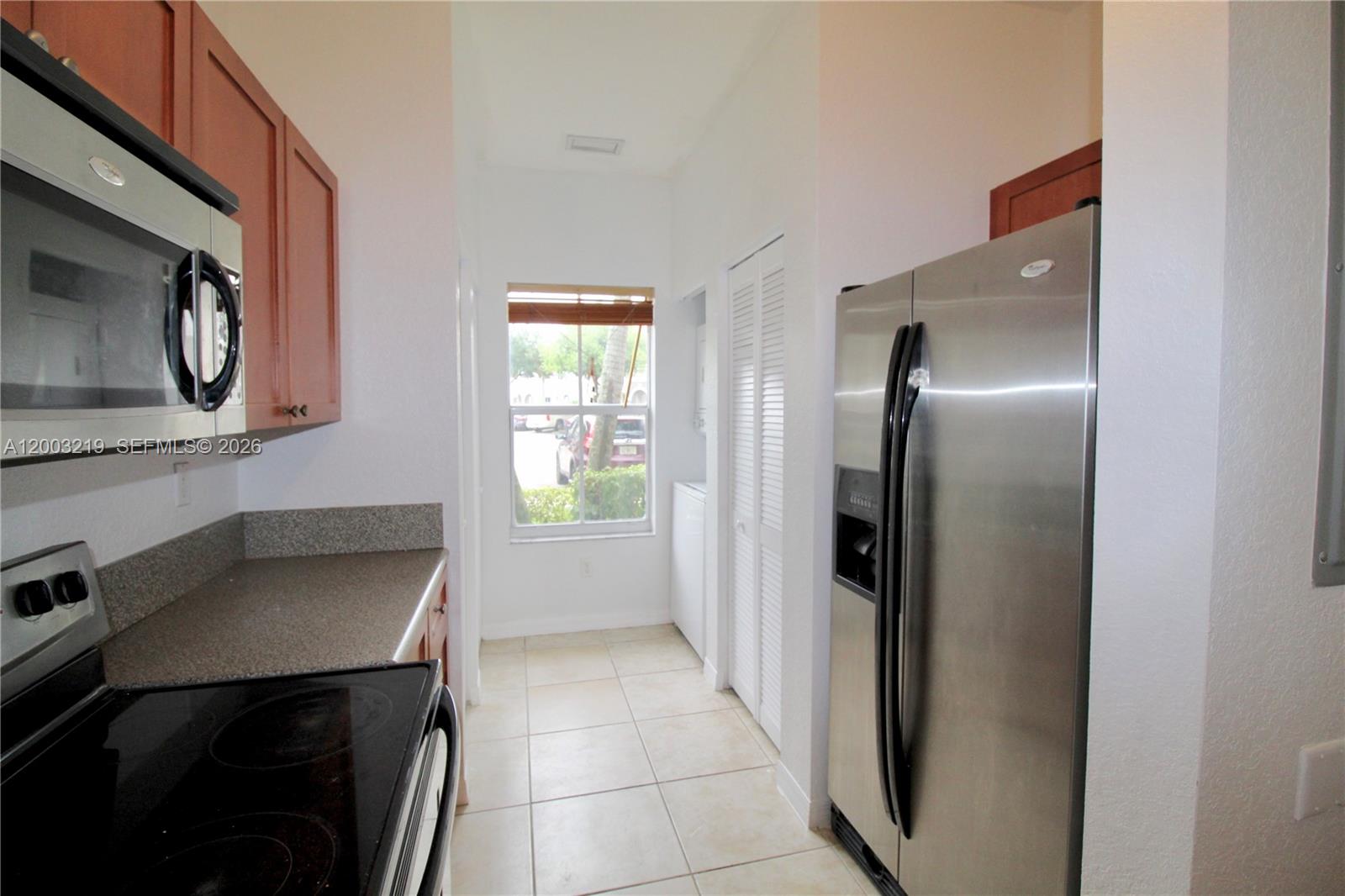 A galley kitchen features stainless steel appliances, wood cabinets, and a window at the end — 14054 SW 49th St # 20, Miramar FL 33027, MIRAMAR, FL