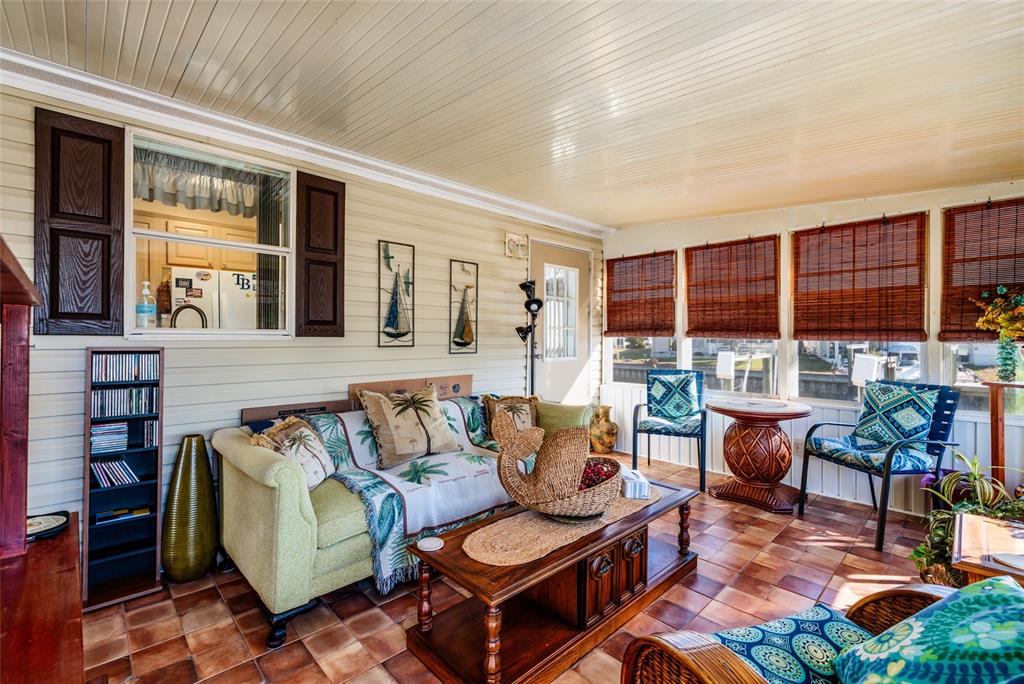 A sunroom with tile flooring, a sofa, a coffee table, and windows with bamboo shades — 134 AMERICANA COURT NE UNIT 216, ST PETERSBURG, FL