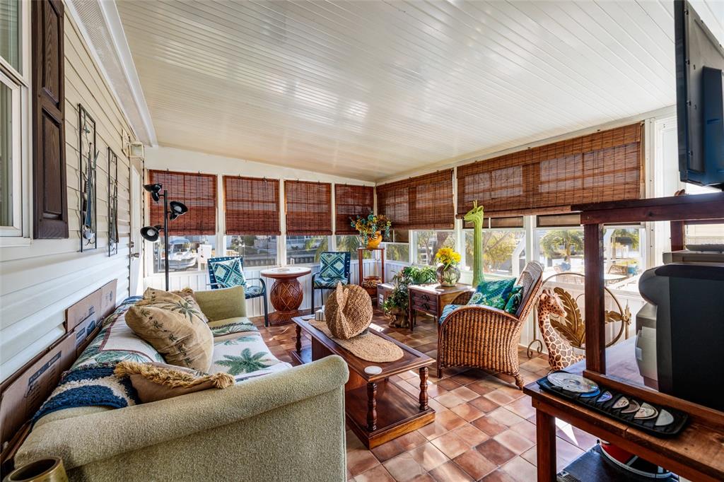 A sunroom features tile flooring, wicker furniture, bamboo shades, and a view of the outdoors — 134 AMERICANA COURT NE UNIT 216, ST PETERSBURG, FL