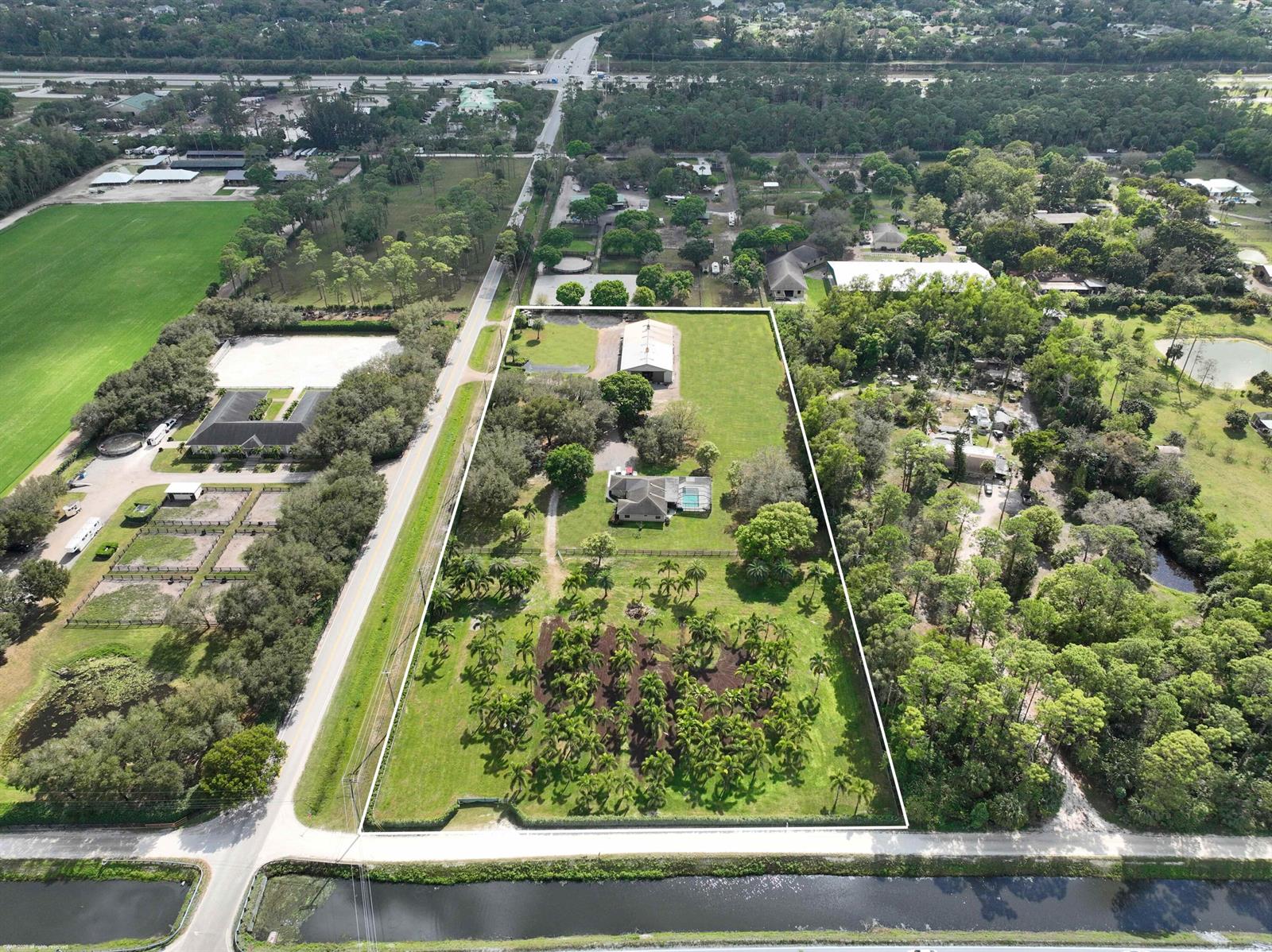 An aerial view shows a residential property with a house, pool, and barn on acreage — 13528 N 6th Court N, FL 33470, FL