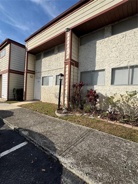 A two-story building features beige stucco walls, brown trim, and a concrete sidewalk — 3990 CRAYRICH CIRCLE UNIT GE, ORLANDO, FL