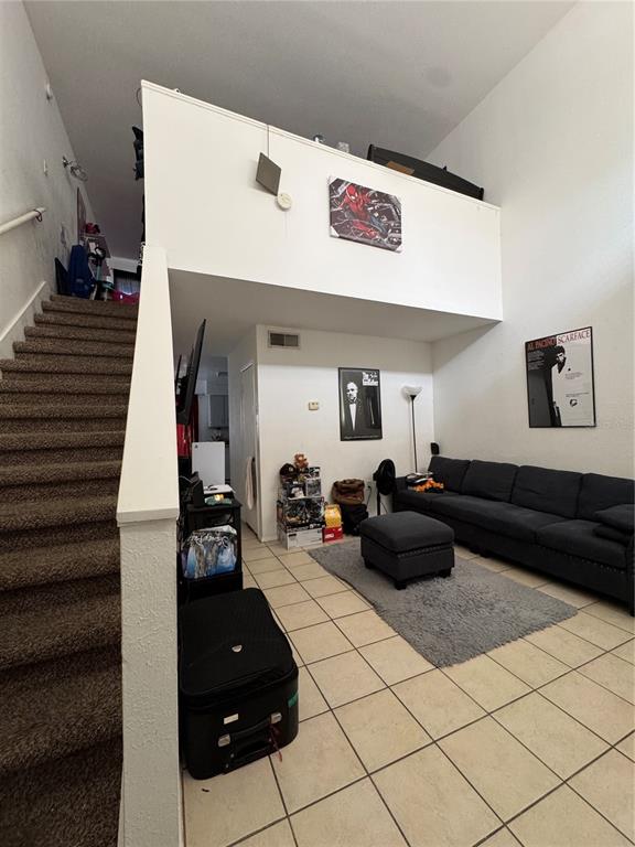 A living room with tile floors, a staircase, and a loft area above the sofa — 3990 CRAYRICH CIRCLE UNIT GE, ORLANDO, FL