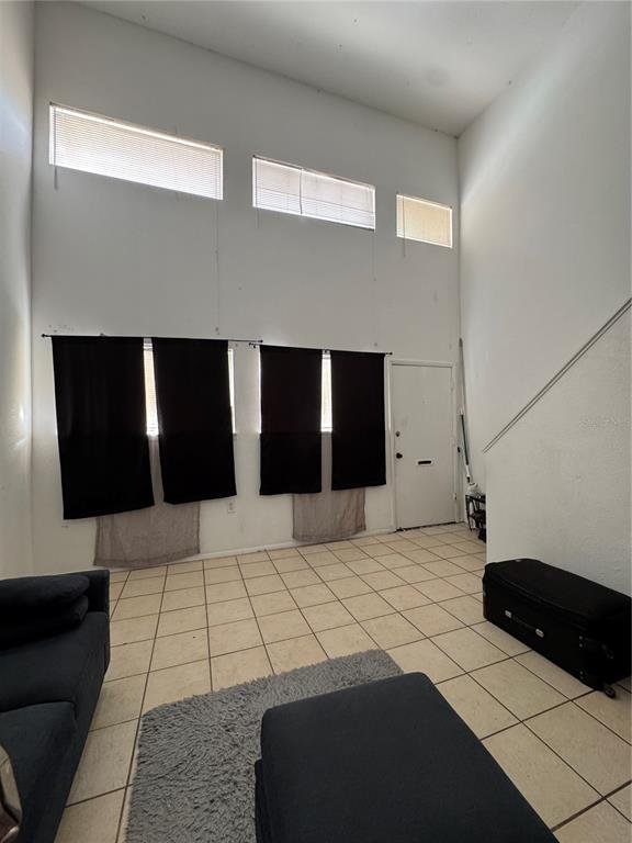 A living room with high ceilings, tile flooring, black curtains, and upper windows — 3990 CRAYRICH CIRCLE UNIT GE, ORLANDO, FL