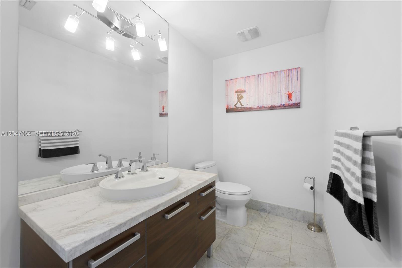 A modern bathroom features a marble-topped vanity, a vessel sink, and a wall-mounted painting — 244 Biscayne Blvd # 451, Miami FL 33132, MIAMI, FL
