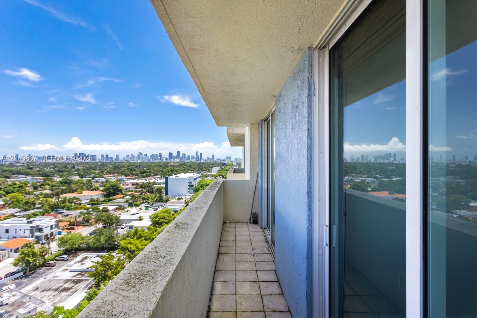 A balcony with tiled flooring and a concrete railing overlooks a city skyline — 3000 CORAL WAY # 1507, Miami FL 33145, MIAMI, FL