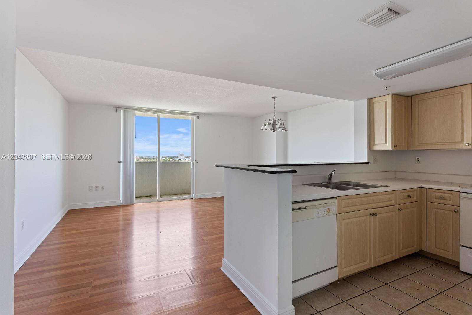 A kitchen with light wood cabinets and a tile floor opens to a living area — 3000 CORAL WAY # 1507, Miami FL 33145, MIAMI, FL