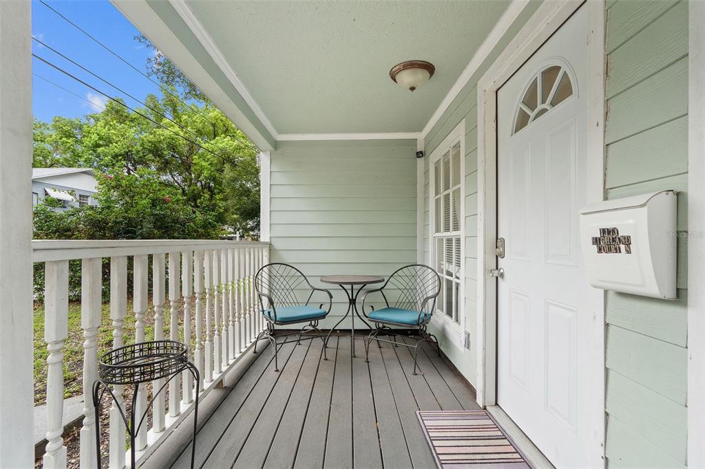 A covered front porch features a small table, two chairs, and a white front door — 1171 HIGHLAND COURT N, ST PETERSBURG, FL