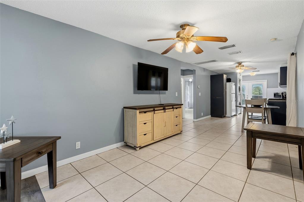 A living room features light blue walls, tile flooring, a ceiling fan, and a media console — 1171 HIGHLAND COURT N, ST PETERSBURG, FL