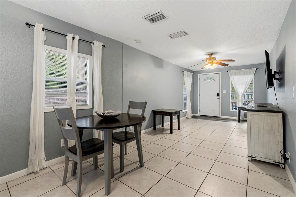 A dining area with a round table, tile flooring, gray walls, and a ceiling fan — 1171 HIGHLAND COURT N, ST PETERSBURG, FL