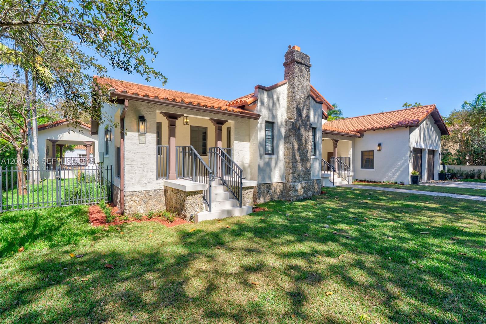 A single-story house with a stone chimney, stucco walls, and a red tile roof — 519 Alhambra Cir, Coral Gables FL 33134, CORAL GABLES, FL