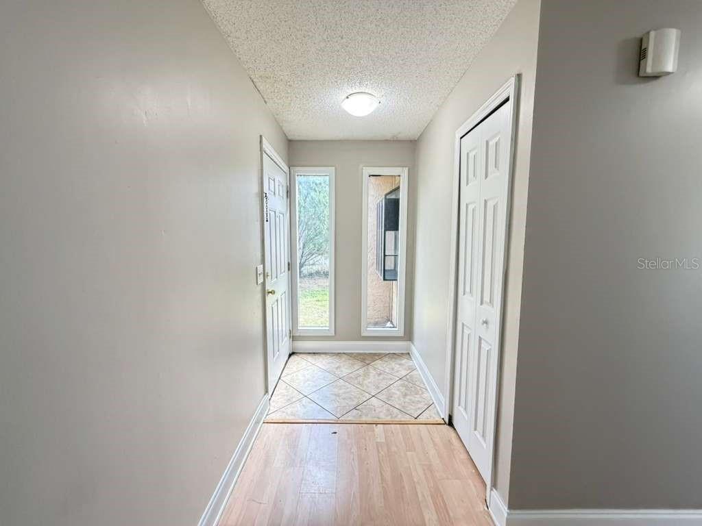 An entryway features light wood flooring, a tiled landing, and a closet with white doors — 118 DAHLIA VILLAGE CIRCLE UNIT 79, ORLANDO, FL