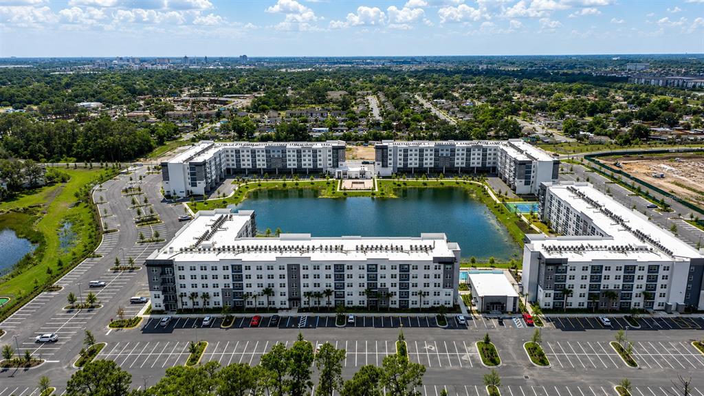 An aerial view shows a large apartment complex surrounding a central pond with parking lots — 5587 MILLENIA PARK BOULEVARD UNIT 503, ORLANDO, FL