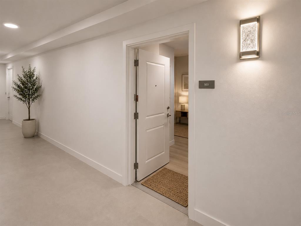 A hallway with white walls, tile flooring, a potted plant, and an open apartment door — 5587 MILLENIA PARK BOULEVARD UNIT 503, ORLANDO, FL