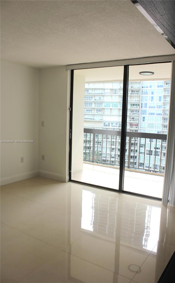 An empty room with light-colored tile flooring features a sliding glass door leading to a balcony — 2333 Brickell Ave # 1004, Miami FL 33129, MIAMI, FL