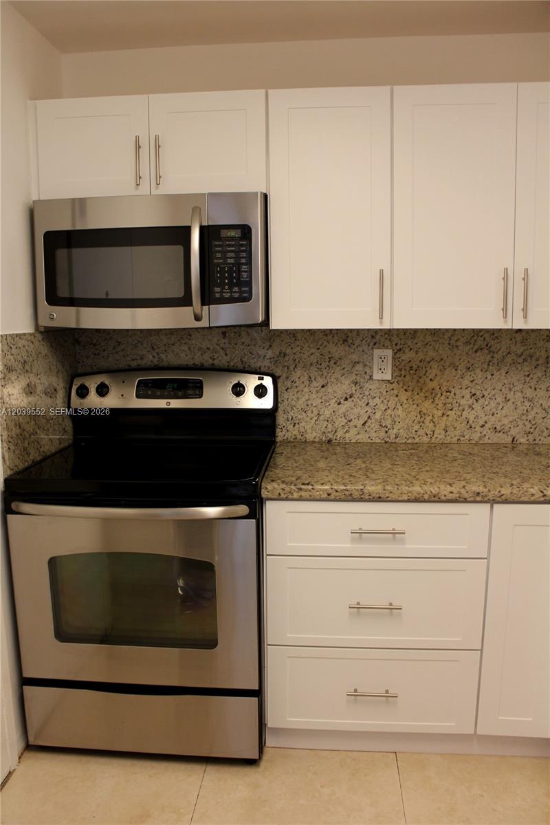 A kitchen features white shaker cabinets, granite countertops, and stainless steel appliances — 2333 Brickell Ave # 1004, Miami FL 33129, MIAMI, FL