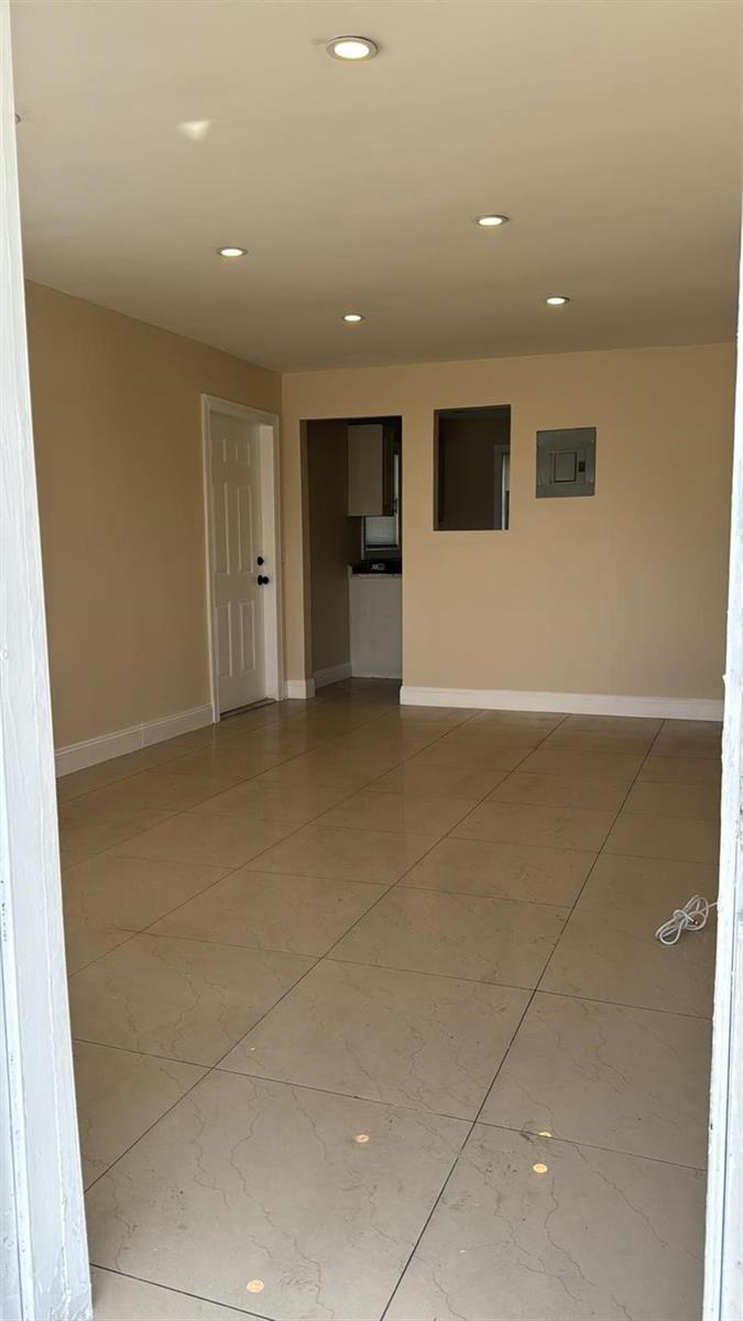 An empty room features beige walls, recessed ceiling lights, and light-colored tiled flooring — 3734 Avenue S, Riviera Beach FL 33404, RIVIERA BEACH, FL