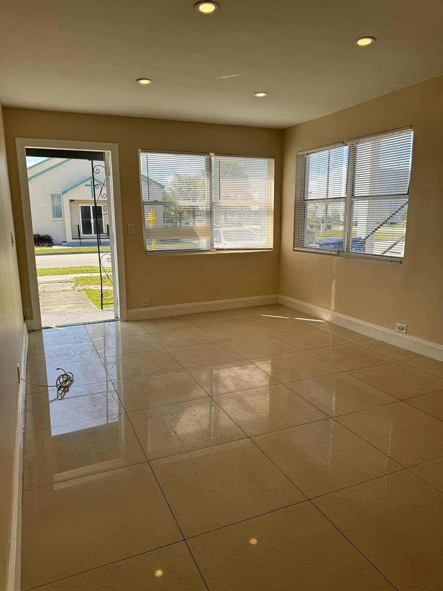 An empty room with beige tile flooring, recessed lighting, and windows with white blinds — 3734 Avenue S, Riviera Beach FL 33404, RIVIERA BEACH, FL
