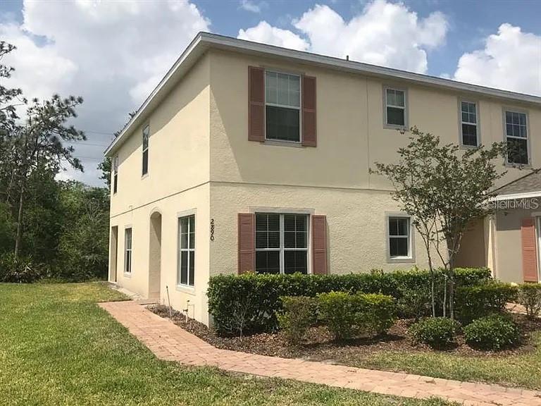 A two-story tan stucco townhouse features brown shutters and a brick walkway — 2890 TANZANITE TERRACE, KISSIMMEE, FL