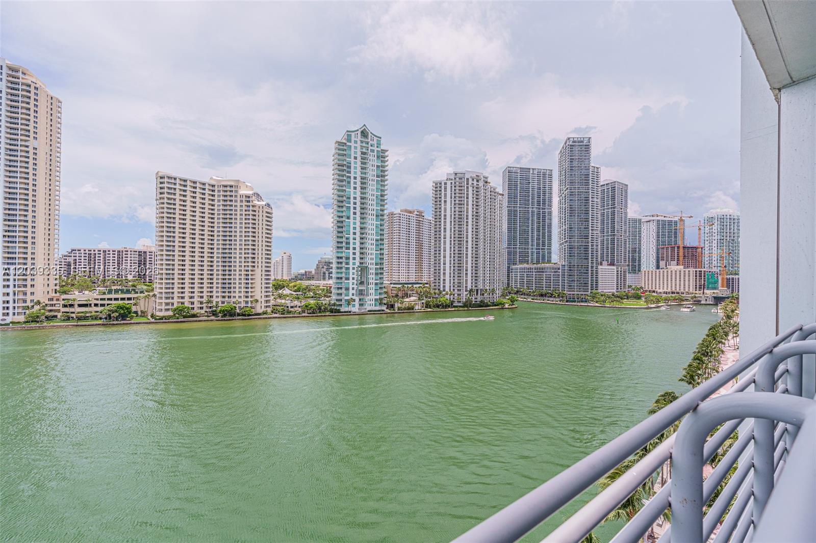 A balcony view overlooks a wide river lined with numerous high-rise apartment buildings — 335 S Biscayne Blvd # 1009, Miami FL 33131, MIAMI, FL