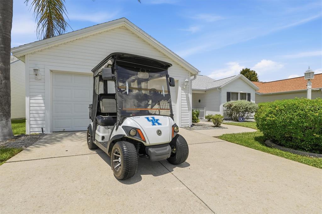 A white golf cart with a University of Kentucky logo sits on a residential driveway — 3425 CARBONDALE COURT, THE VILLAGES, FL