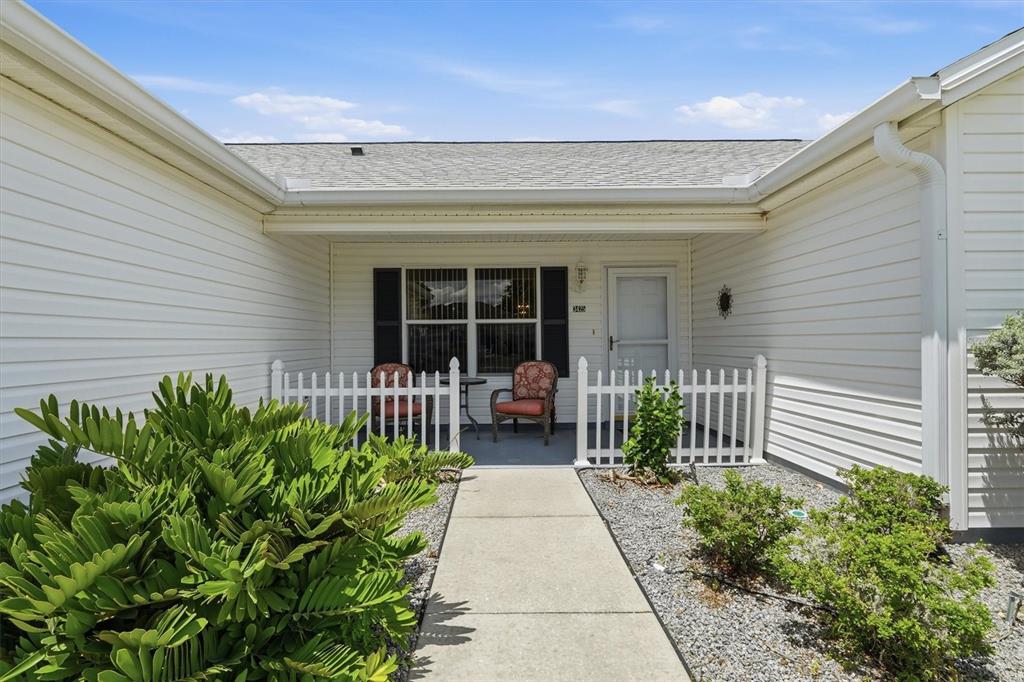 A concrete walkway leads to the front porch of a white house with a fence — 3425 CARBONDALE COURT, THE VILLAGES, FL