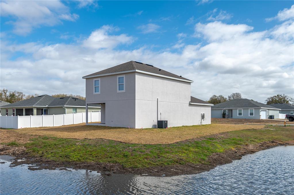 A two-story house with a light-colored exterior sits on a lot beside a pond — 2169 SUTTON RIDGE AVENUE, LAKELAND, FL