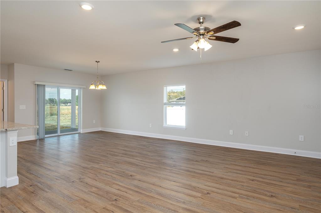 An open-concept living and dining area features wood-look flooring, a ceiling fan, and sliding doors — 2169 SUTTON RIDGE AVENUE, LAKELAND, FL