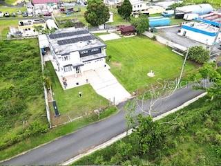 An aerial view shows a two-story house with solar panels on a large grassy lot — 927 ANTON RUIZ UNIT KM 27.7, HUMACAO, PR