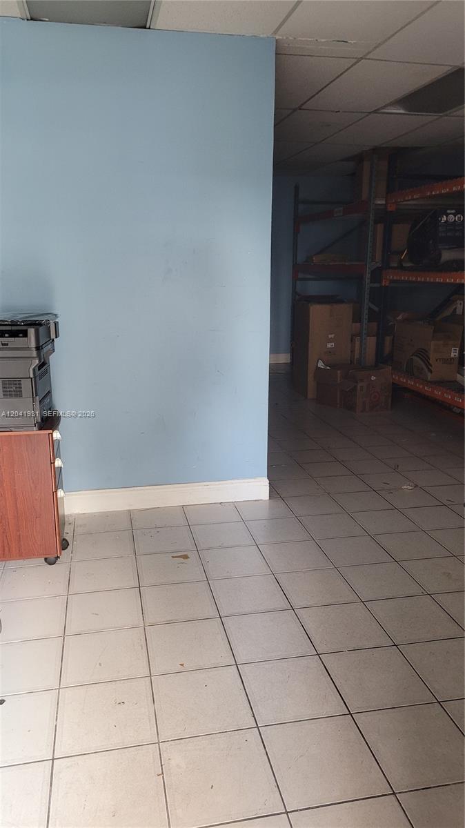 A room with light blue walls, tiled flooring, and metal shelving units holding cardboard boxes — 1169 W 37th St # 1181, Hialeah FL 33012, HIALEAH, FL