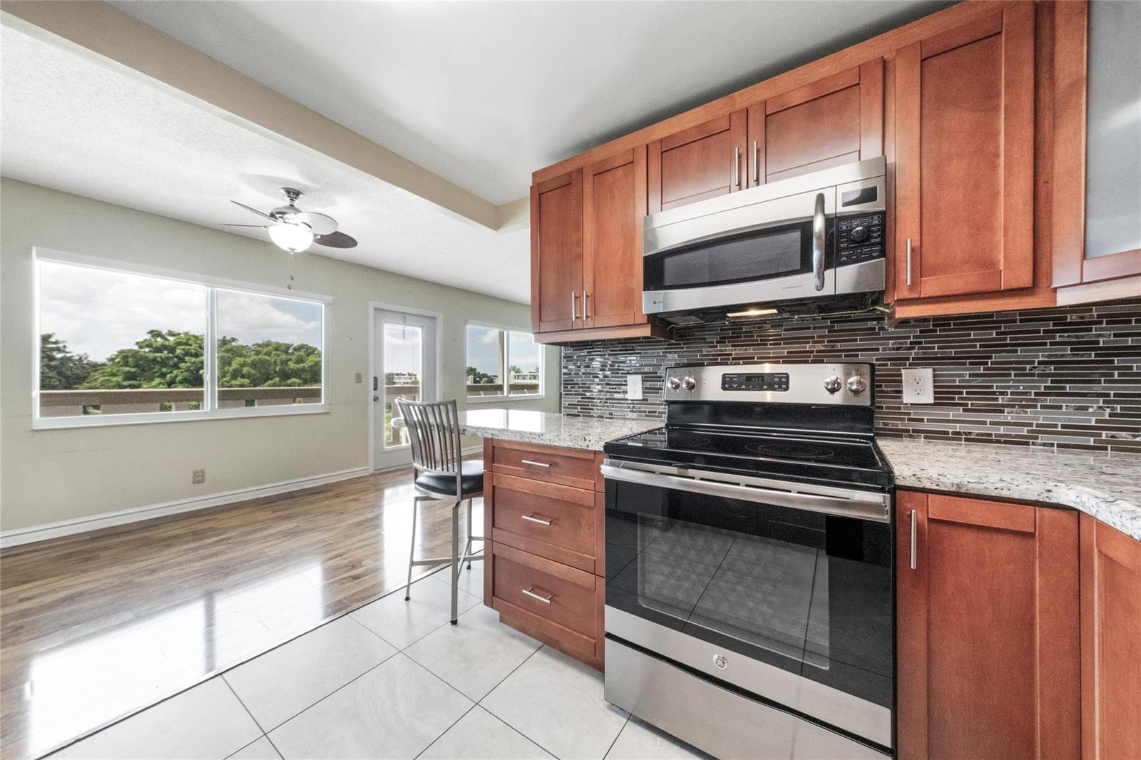 A kitchen with wood cabinets, stainless steel appliances, and a breakfast bar overlooking a balcony — 404 Richmond A # 404, Deerfield Beach FL 33442, DEERFIELD BEACH, FL