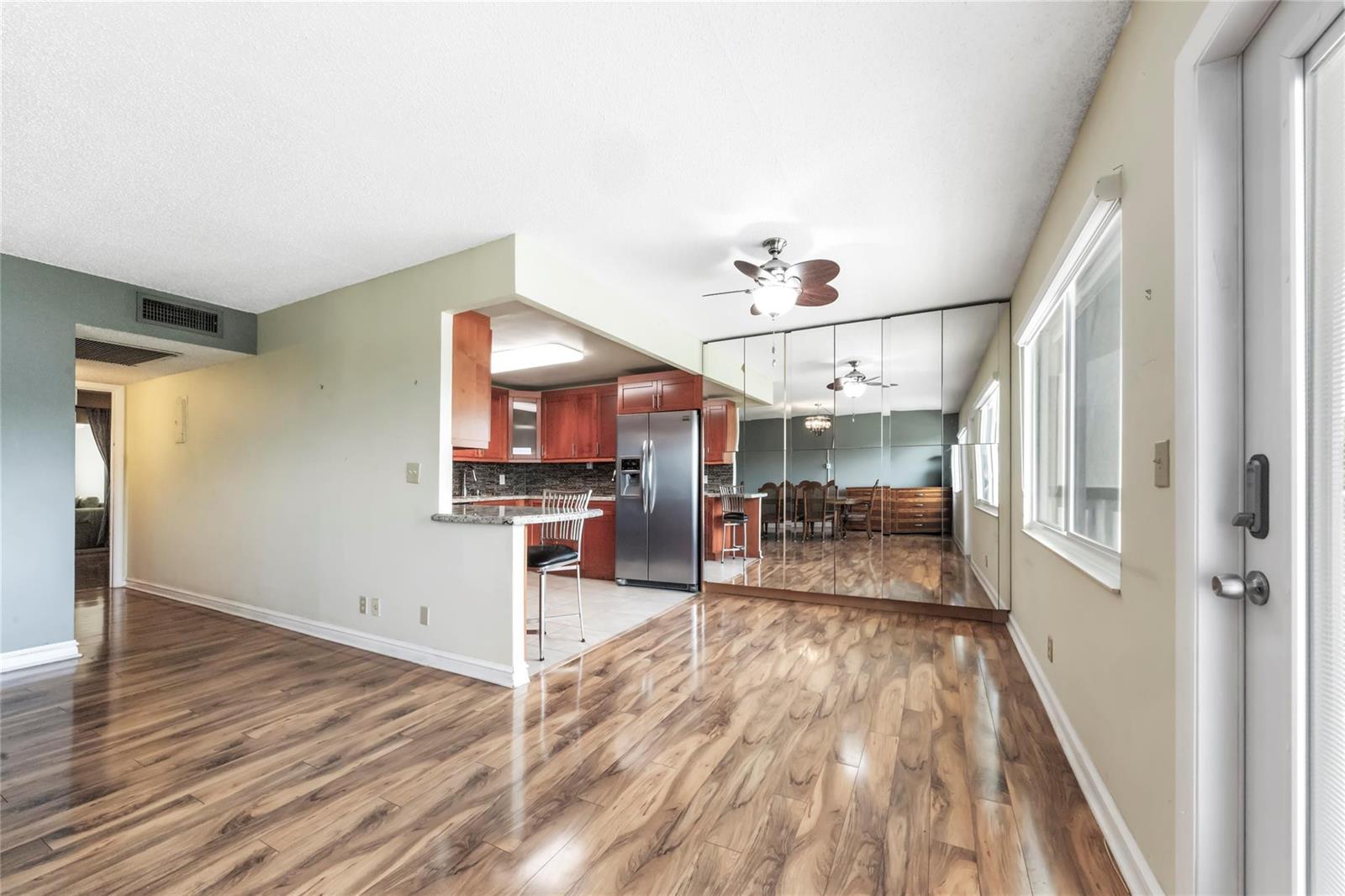 A kitchen with wood cabinets and stainless steel appliances opens to a room with mirrors — 404 Richmond A # 404, Deerfield Beach FL 33442, DEERFIELD BEACH, FL