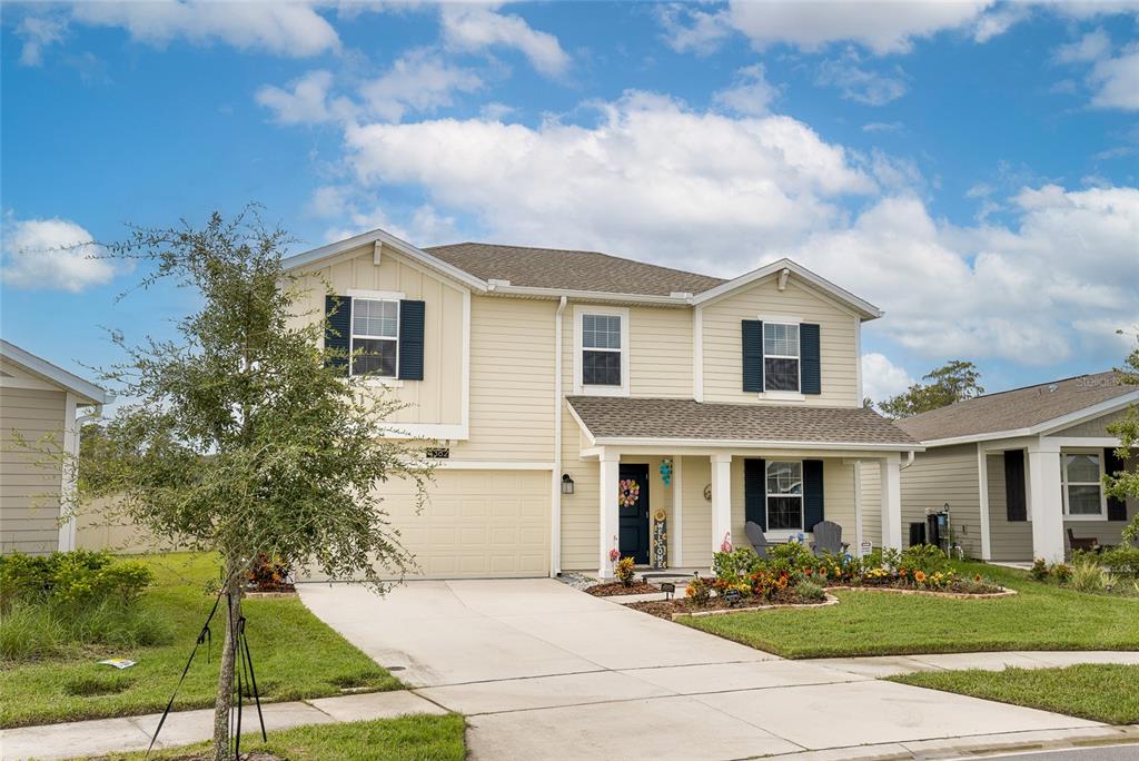 A two-story, light yellow house with a front porch, garage, and dark blue shutters — 4382 FINCH LANE, KISSIMMEE, FL