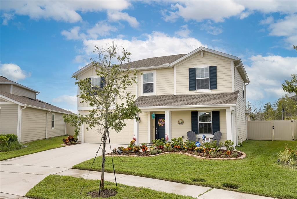 A two-story house with beige siding, dark shutters, a front porch, and a landscaped yard — 4382 FINCH LANE, KISSIMMEE, FL