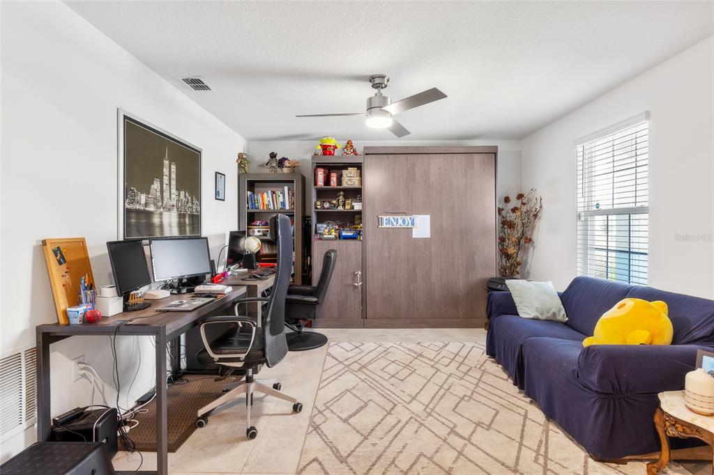 A home office features a desk, a Murphy bed, a blue sofa, and a ceiling fan — 4382 FINCH LANE, KISSIMMEE, FL